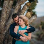 romantic couple hugging in front of a palm tree in the desert